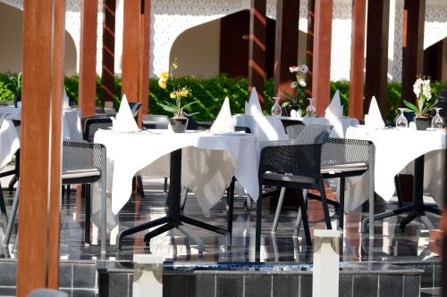 a row of white tables and chairs with flowers on them at Falaj Daris Hotel in Nizwa