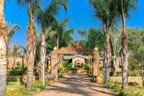 um arco que leva a uma casa com palmeiras em Maretlwane Guesthouse em Buffelspoort