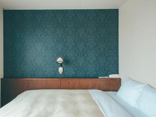- une chambre avec un lit et un mur vert dans l'établissement Toyohashi Station Hotel / Vacation STAY 65494, à Toyohashi