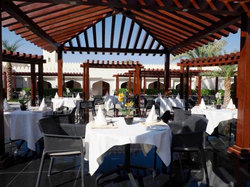 a restaurant with white tables and chairs and a pavilion at Falaj Daris Hotel in Nizwa