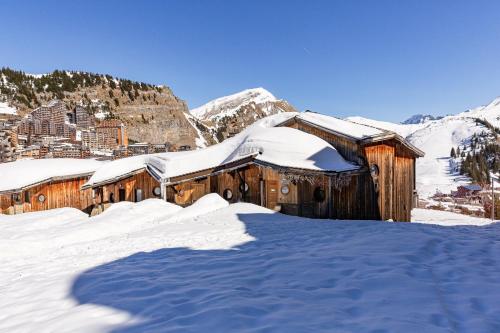 a wooden building covered in snow with mountains in the background at Luxury Avoriaz Chalet with hot tub in Avoriaz