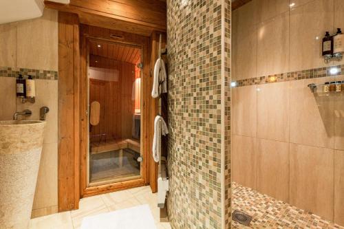 a bathroom with a shower and a tiled wall at Luxury Avoriaz Chalet with hot tub in Avoriaz