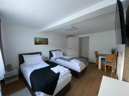 Cette chambre comprend 2 lits et une table. dans l'établissement Apartment Q im Zentrum von Königsbronn, à Königsbronn