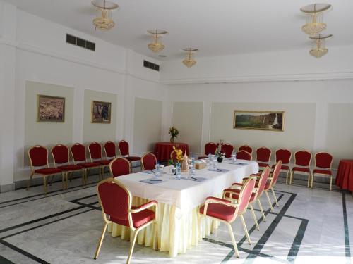 a conference room with a table and red chairs at Falaj Daris Hotel in Nizwa