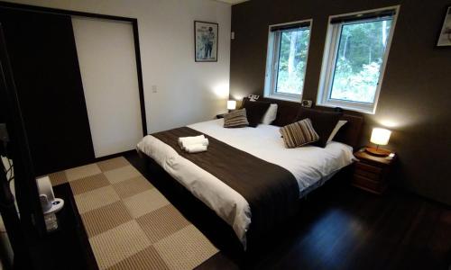 a bedroom with a large bed and two windows at Avanti Chalet 白馬 in Hakuba