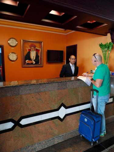 two men waiting at a counter in an airport at Falaj Daris Hotel in Nizwa
