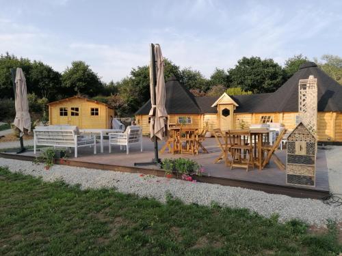 une terrasse avec des tables et des parasols en face d'une maison dans l'établissement Au Coin du Bois, à Langolen