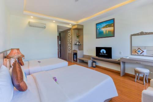 a bedroom with a white bed and a television at Sky Beach D20 Nha Trang in Nha Trang