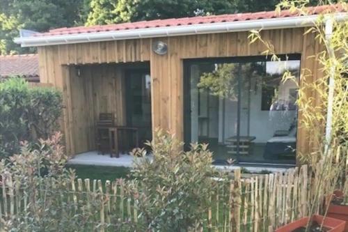 a small wooden shed with a fence at Charmante Cabane Bois in Gujan-Mestras