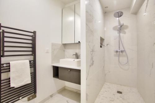 a white bathroom with a sink and a shower at 1 Bedroom Louvre Saint Honoré in Paris
