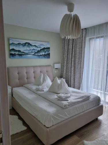 a white bed in a bedroom with a large window at Eminescu Premium Luxury Apartments in Buşteni