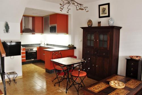 eine Küche mit roten Schränken sowie einem Tisch und Stühlen in der Unterkunft Encantador adosado en Gran Alacant in Gran Alacant