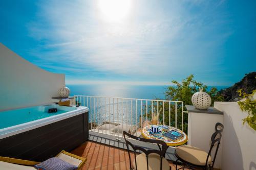 a balcony with a hot tub and chairs and the ocean at Villa Fortuna in Positano