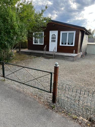 una piccola casa con una recinzione di fronte di Chalet Charmant Monika avec Piscine a Yvoir