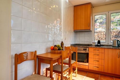 a kitchen with a wooden table and chairs and a table and a bowl of fruit at Largo dos Milagres, a Home in Madeira in Machico