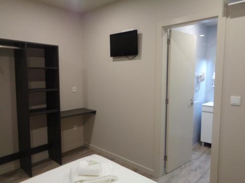 a room with a tv on the wall and a bathroom at Rua Grande Hotel in Viana do Castelo