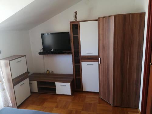 1 dormitorio con armario, TV y escritorio en Apartmani Slavica, en Jezera