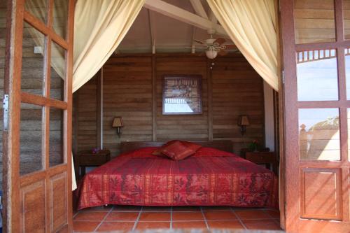 a bedroom with a bed with a red bedspread at Statia Lodge in Oranjestad