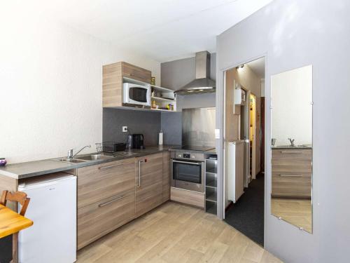 une cuisine avec des appareils en acier inoxydable et des armoires en bois dans l'établissement Appartement lumineux 6 pers plein centre, pied des pistes, balcon, vue montagne - FR-1-400-112, à Eaux-Bonnes
