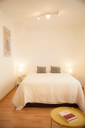 Un dormitorio con una gran cama blanca y una mesa en Luxor 7, en Sevilla