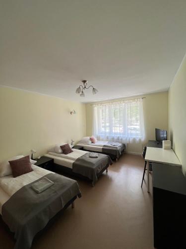 Habitación con 3 camas, escritorio y TV. en Abra IV Apartament, en Poznan