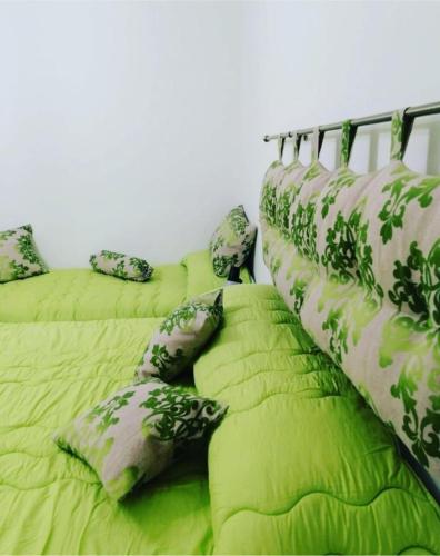 a row of beds with green sheets and pillows at Il Quadrifoglio di Triveri in Bovalino Marina