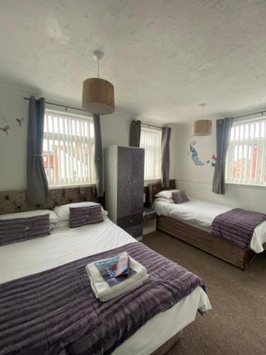 a bedroom with two beds and two windows at Mayfair Hotel in Blackpool