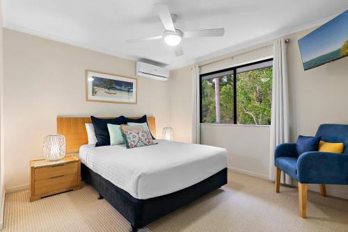 een slaapkamer met een bed en een blauwe stoel bij Tropical Retreat in 2 Bedroom Townhouse in Noosaville