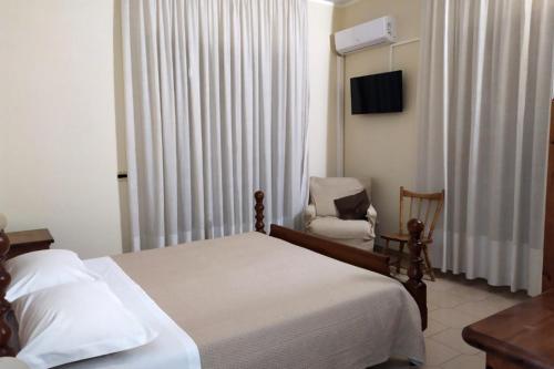 una camera con letto, sedia e televisore di Hotel Casa Del Gourmet a Siderno Marina