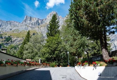 a street with flowers and a mountain in the background at Hotel Astoria in Leukerbad