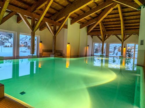 a swimming pool in a large room with wooden ceilings at Ferienwohnung in den Bergen mit grosser Terrasse in Bivio