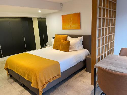 a bedroom with a bed with a yellow blanket on it at Chambres d’hôtes les Grisons in Houyet
