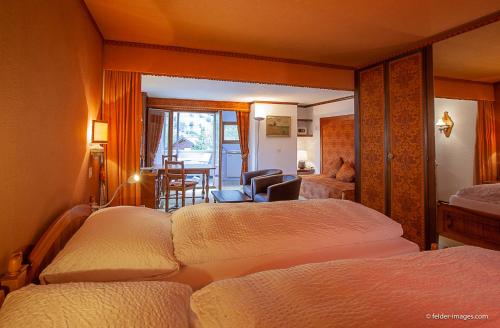 a hotel room with two beds and a chair at Hotel Astoria in Leukerbad