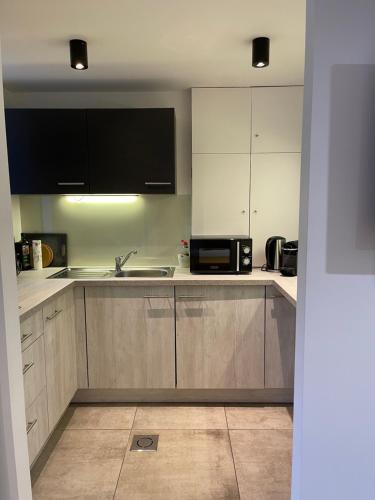 a kitchen with white cabinets and a sink and a microwave at Chambres d’hôtes les Grisons in Houyet