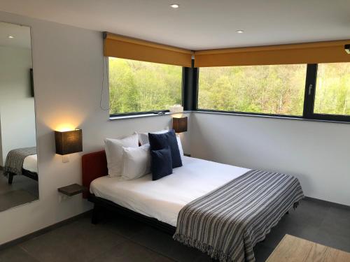 een slaapkamer met een bed en een groot raam bij Chambres d’hôtes les Grisons in Houyet