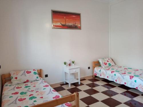 a bedroom with two beds and a checkered floor at Grand Appartement à 5 mn de la plage in Agadir