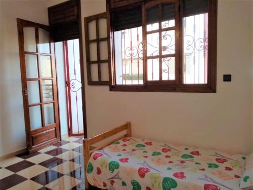 a bedroom with a bed in a room with windows at Grand Appartement à 5 mn de la plage in Agadir