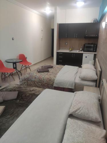 a room with two beds and a table and a kitchen at G M 3 ROOMS KENTPO in the heart of the city in Larisa