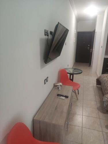 a living room with red chairs and a tv on the wall at G M 3 ROOMS KENTPO in the heart of the city in Larisa