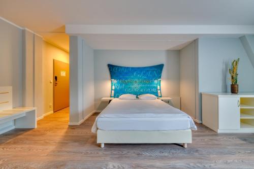 a bedroom with a white bed with a blue headboard at Ibis Styles Regensburg in Regensburg