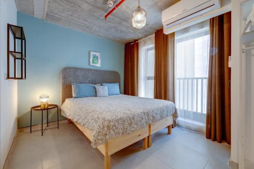 a bedroom with a bed with blue walls and a window at Sliema Creek Suites in Sliema