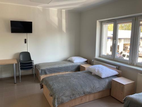 a room with two beds and a television and a desk at Hostel przy Stadionie in Jaworzno