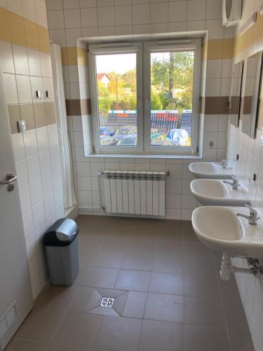 a bathroom with a row of sinks and a window at Hostel przy Stadionie in Jaworzno