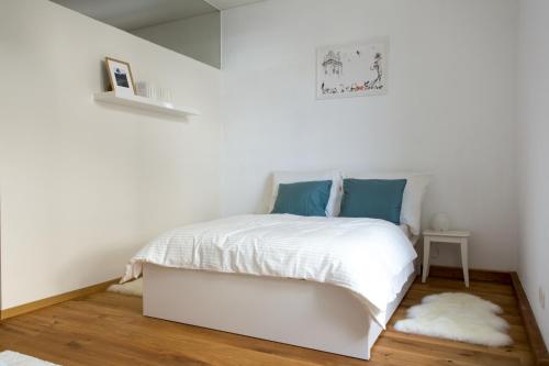 ein weißes Schlafzimmer mit einem weißen Bett und blauen Kissen in der Unterkunft Charming City Apartment in Graz