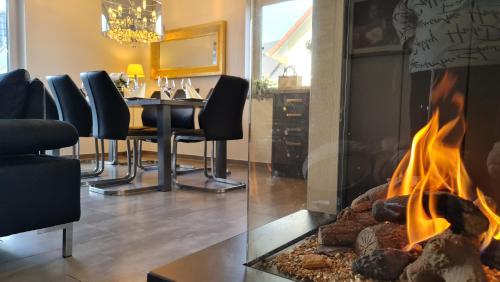 a fireplace in a living room with a table and chairs at Luxusferienhaus Seevilla Monaco am Fleesensee in Göhren-Lebbin
