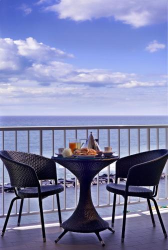 a table and chairs on a balcony with the ocean at Hotel La Baia in Diano Marina