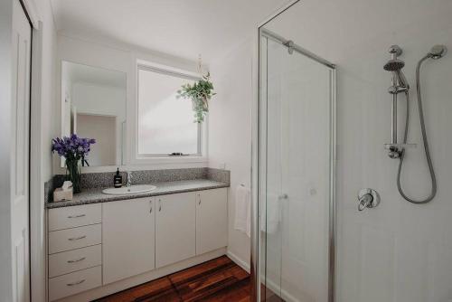 a white bathroom with a sink and a shower at House on Hampson in Penguin