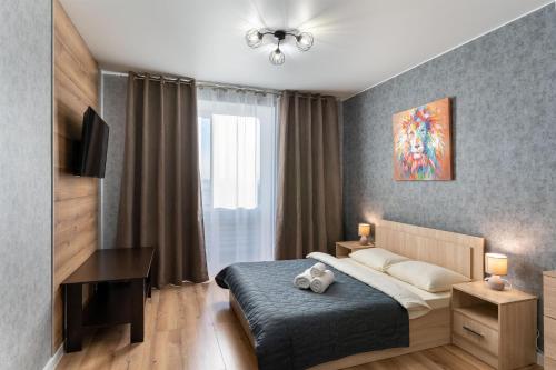 a bedroom with a bed and a desk and a window at Апартаменты в новом жилом комплексе Кристалл in Tyumen