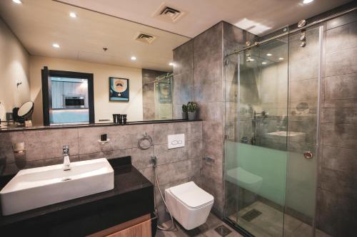 a bathroom with a sink and a glass shower at A&H Hotel Apartment in Doha
