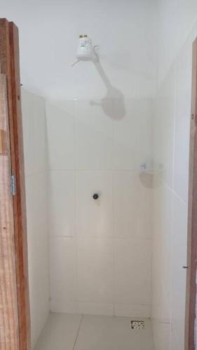 a white bathroom with a light on the wall at Chalés Vila Irerê Itaúnas in Itaúnas